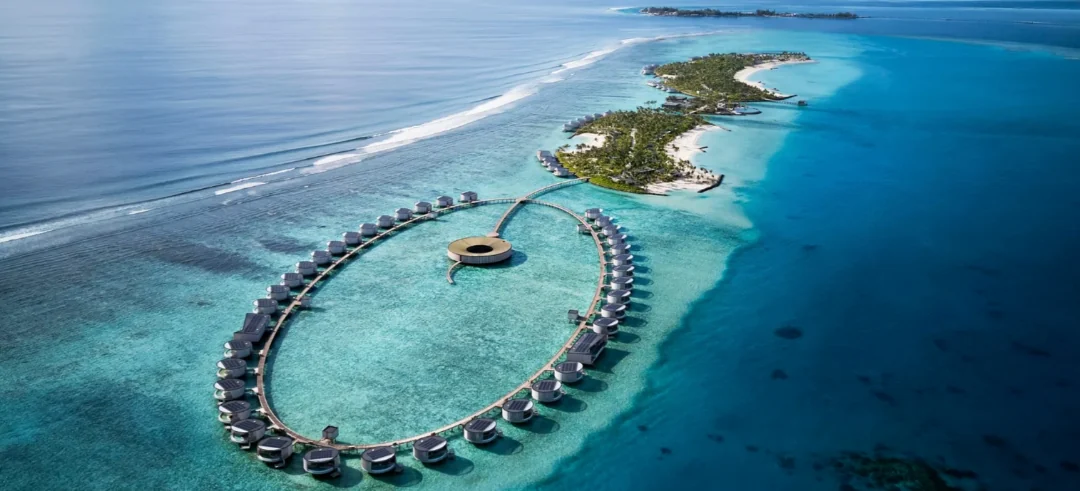 Vista aérea de resort nas Maldivas com bangalôs sobre águas cristalinas e ilha tropical
